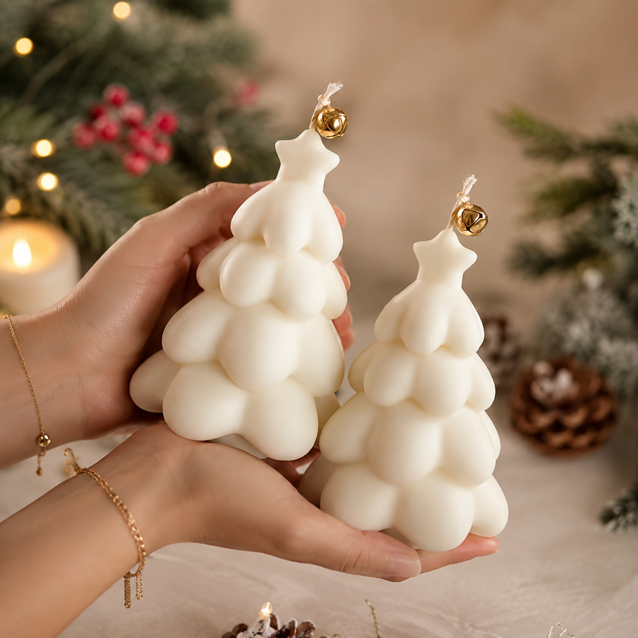 Snowtree luxury ivory handmade soy wax Christmas tree candle set with gold bell detail displayed on natural travertine in a luxury festive studio setting.