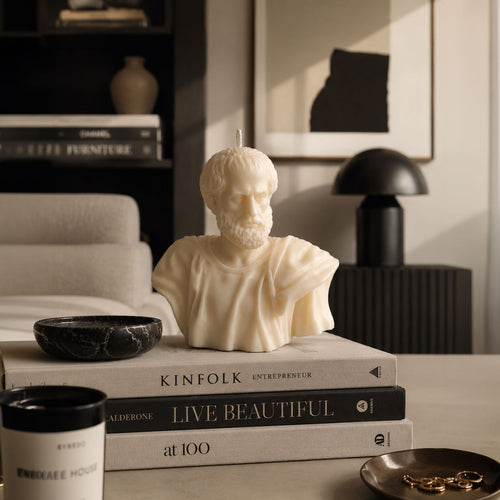 Aristotle Bust Candle displayed on coffee table books in a modern luxury interior, artisan Greek philosopher candle by Warm Warren London.