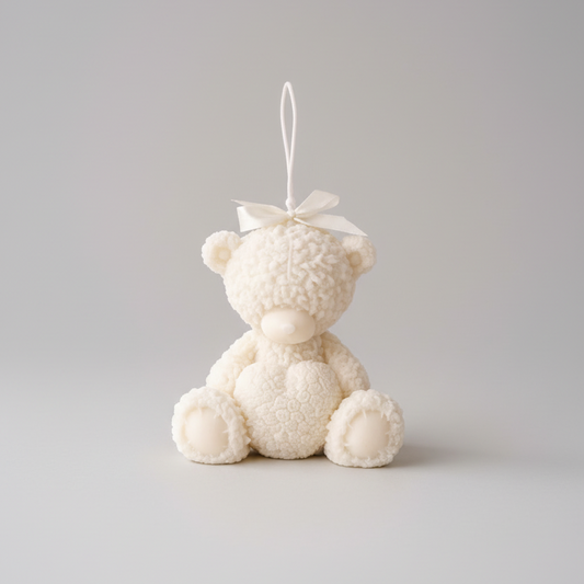 Small white teddy bear ornament on a wooden surface with a blurred background